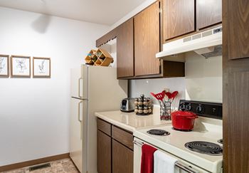 A kitchen with wooden cabinets and a white stove top oven